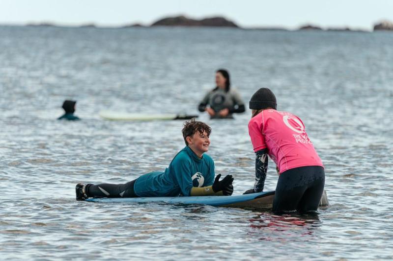 Surfer lying on a board with an instructor talking to them