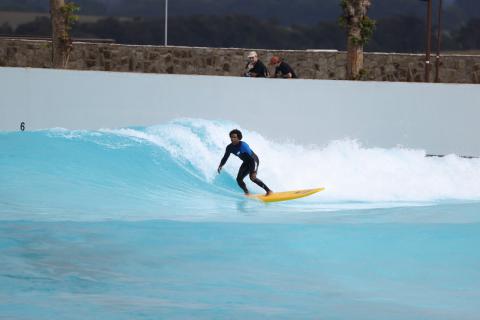 Surfer on a board, riding a wave in a Wavegarden cove